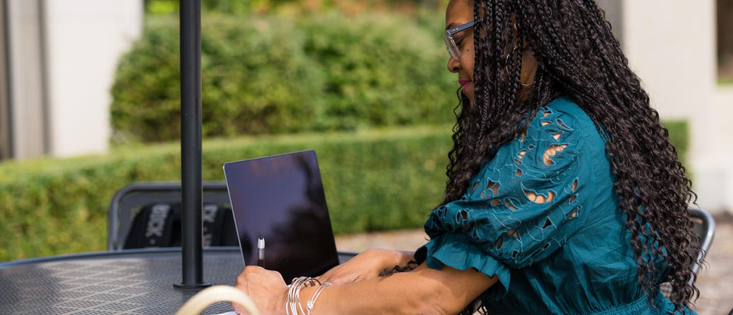 Woman typing on a laptop outside the Oakland Center